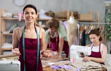Female seamstress invites others to sew and work in her sewing workshop