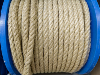 Natural fiber rope tightly wound on a blue spool ready for various applications in outdoor...