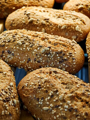 Freshly baked whole grain bread rolls with seeds displayed in a bakery