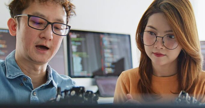 Asian male, female programming developer work together at home office, coding robotic arm machine. Information technology, software engineer programmer job, man woman coworker teamwork concept