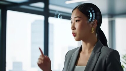 Asian woman in suit speaks and gestures with futuristic brain particles in office - Powered by Adobe