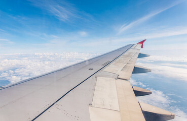 View from the airplane window at a beautiful cloudy sky and the airplane wing