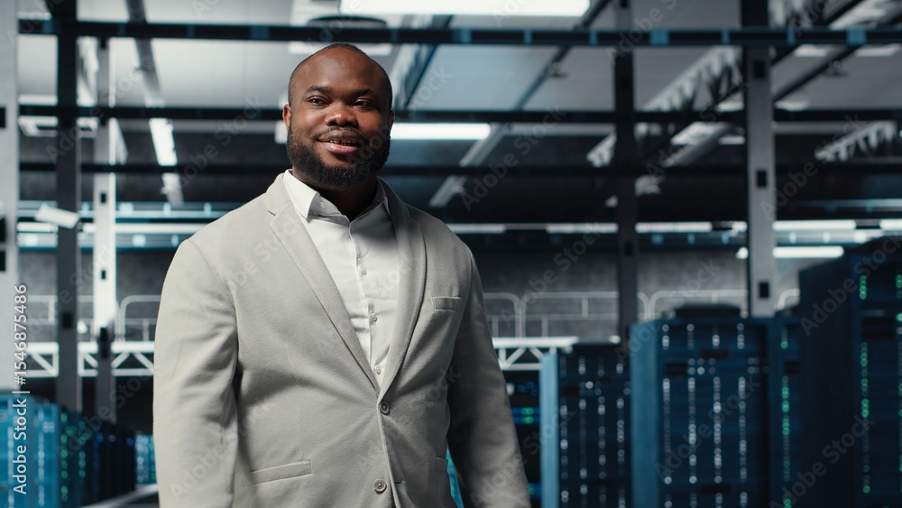 Poster smiling engineer walking in data center, checking hardware for system stability. happy employee over