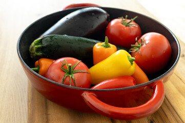 red beautiful cast iron skillet and fresh vegetables. cooking vegetable stew in cast iron. fresh...