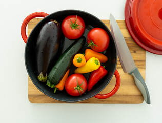 red beautiful cast iron skillet and fresh vegetables. cooking vegetable stew in cast iron. fresh...