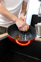 man in kitchen trying to clean food burnt to cast iron pan, hand washing cast iron cookware