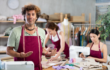 Male seamstress invites others to sew and work in her sewing workshop