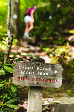 A girl hikes on a trail behind a trail sign on the Daniel Boone Scout Trail to Calloway Peak near Boone, North Carolina