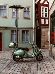 Green retro scooter on empty cobblestone street in charming European town
