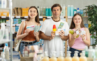 Father, mother and daughter choose different products together in pharmacy
