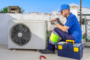 Hvac technician performing air conditioner maintenance inspection on the rooftop. Breakdowns repair...