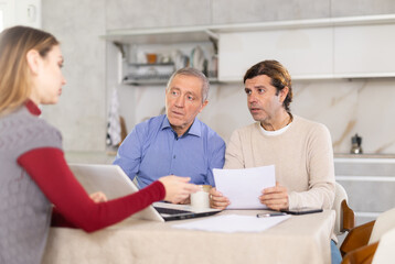 Two men listen attentively to saleswoman talking about the advantages of taking out microloan from a credit institution