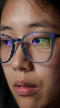 Code reflects in a programmers glasses as they intensely work on a laptop, illuminated by complex data visualizations and scrolling lines of programming text.
