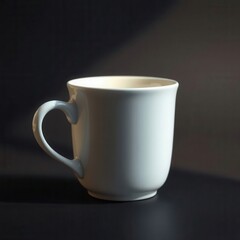 Fototapeta premium A simple, elegant white mug sits on a dark surface, softly illuminated by a gentle light source.