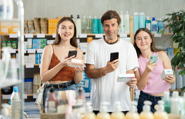 Near display case in pharmacy, family scans barcode on tablet pills package, reads user manual....