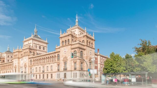 Panorama showing Cavalry Academy timelapse in Plaza de Zorrilla, Valladolid, Spain. Historic military building with intricate architecture, surrounded by busy urban scene under a blue sky with clouds