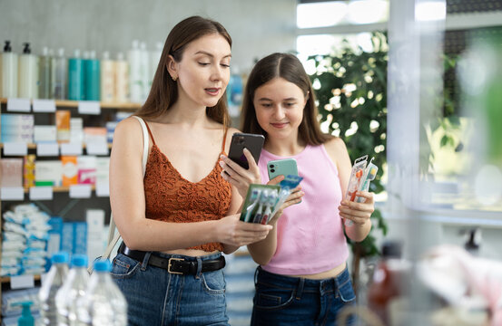 Mother and a teenage daughter scan the barcode of a set of toothbrushes on their phones for online payment in a mobile application.