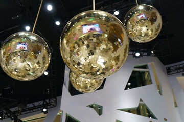 Glistening golden disco balls suspended from a high, modern ceiling.