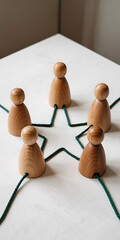 Obraz premium Five Light Wood Figures Connected by Green Cord on White Surface