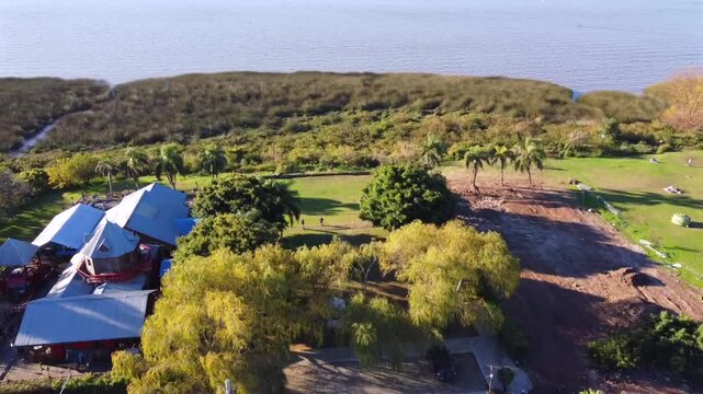 Drone view of demolished Catalejo space and BarIsidro roofs in San Isidro. See roundabout, vehicles, people, coast, vegetation, and sediments. A site in transformation.