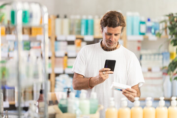 European man in summer clothes holds a mobile phone and scans the barcode on a package of ointment...
