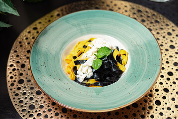 Elegant plate of black and yellow tagliatelle.