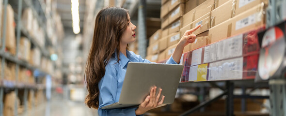 Female engineer is handling shipping and checking stock inventory in the warehouse with a laptop,...