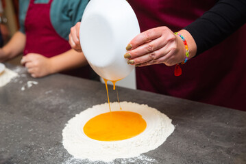 Pouring eggs into flour for homemade pasta.