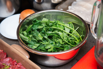 Fresh parsley and basil leaves in metal bowl.