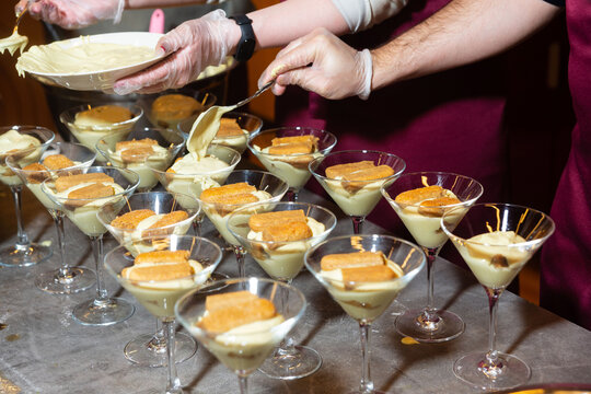 Preparing individual tiramisu desserts in glasses.