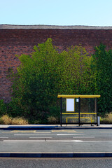 Yellow and black bus stop is in front of a brick building