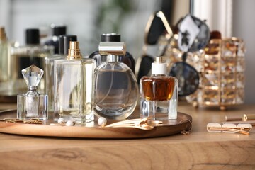 Bottles of different perfumes and accessories on wooden table, closeup