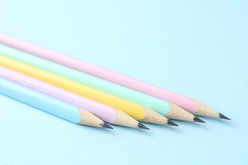 Many graphite pencils on light blue background, closeup