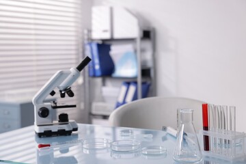 Petri dishes, microscope and test tubes on white table in laboratory