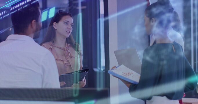 Four executives reviewing in glass office, with tablet clipboard laptop and data overlays
