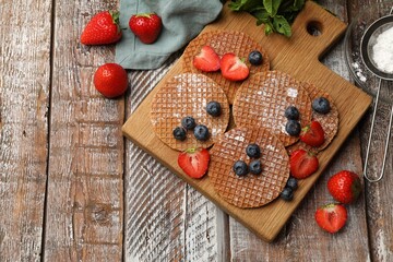 Tasty Dutch waffles (stroopwafels), mint and berries on wooden table, flat lay. Space for text