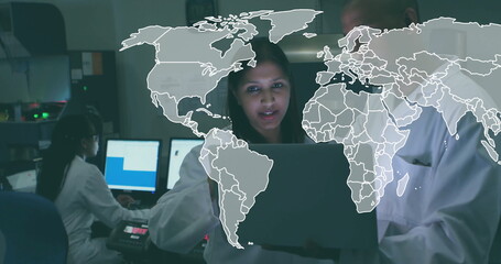 Lab coat researchers examining data on monitors and laptop in laboratory, with digital map overlay