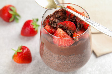 Delicious chocolate pudding with chia seeds and strawberries on light grey table, closeup. Space for text