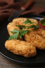 Tasty fried croquettes, parsley and sauce on wooden table, closeup