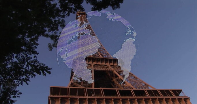 Framing Eiffel Tower rising against blue sky in Paris, with tree branches and digital globe overlay - Powered by Adobe