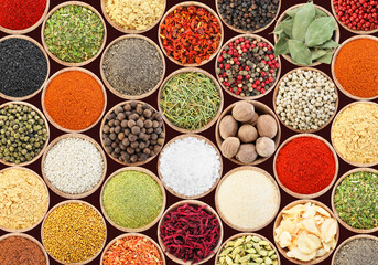 Set of different aromatic spices in bowls on black background, flat lay