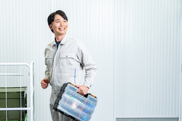 工具箱を持つ作業着を着た男性