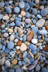 Multicolored pebbles cover the rocky beach, showcasing a variety of shapes, sizes, and hues. Smooth and textured stones create a visually appealing landscape. Generative AI.