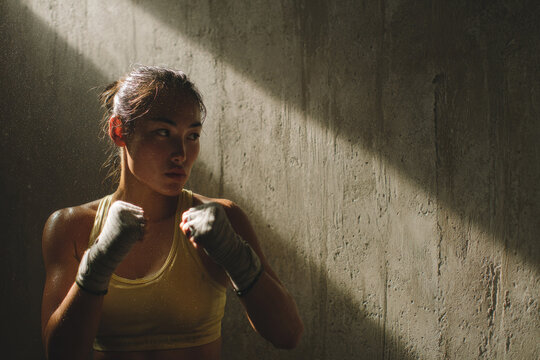 Asian Female Boxer Shadow Boxing in Moody Light with Wrapped Hands
