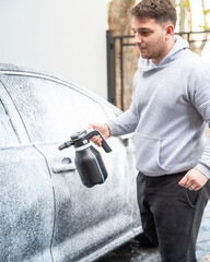 Spraying soap foam on a car with an electric foamer