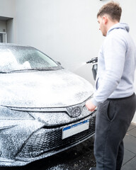 Spraying soap foam on a car with an electric foamer