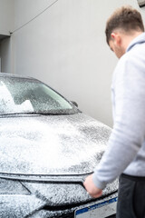 Spraying soap foam on a car with an electric foamer