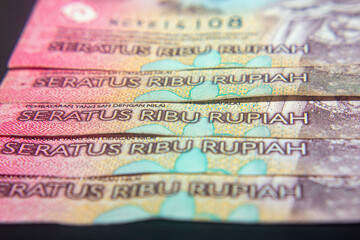 Close-up of Indonesian 100,000 Rupiah banknotes in pink tones.
