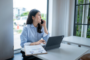 Obraz premium woman is talking on her cell phone while sitting at a desk