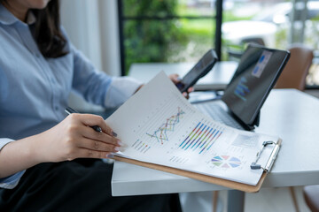 woman is sitting at a table with a clipboard and a laptop